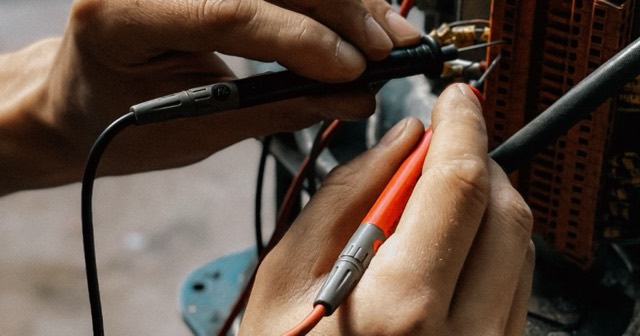 Elektronik donanım bileşenini ölçüm problarıyla kontrol eden teknik servis uzmanının elleri