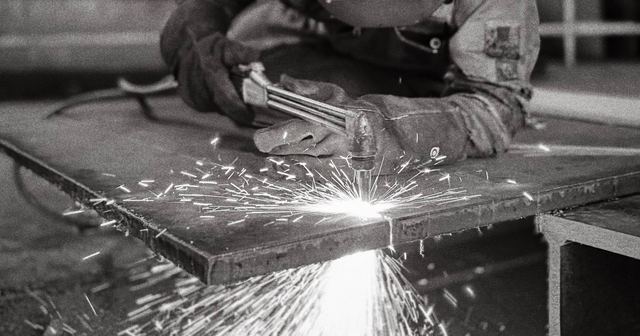 Metal parça üzerinde kaynak yapan maskeli çalışan