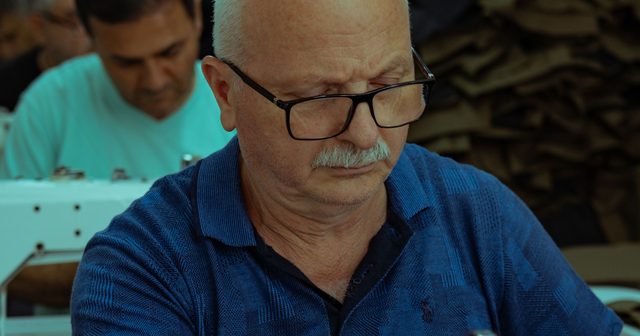 Dikiş makinesinde çalışan terzi ve arka plandaki atölye
